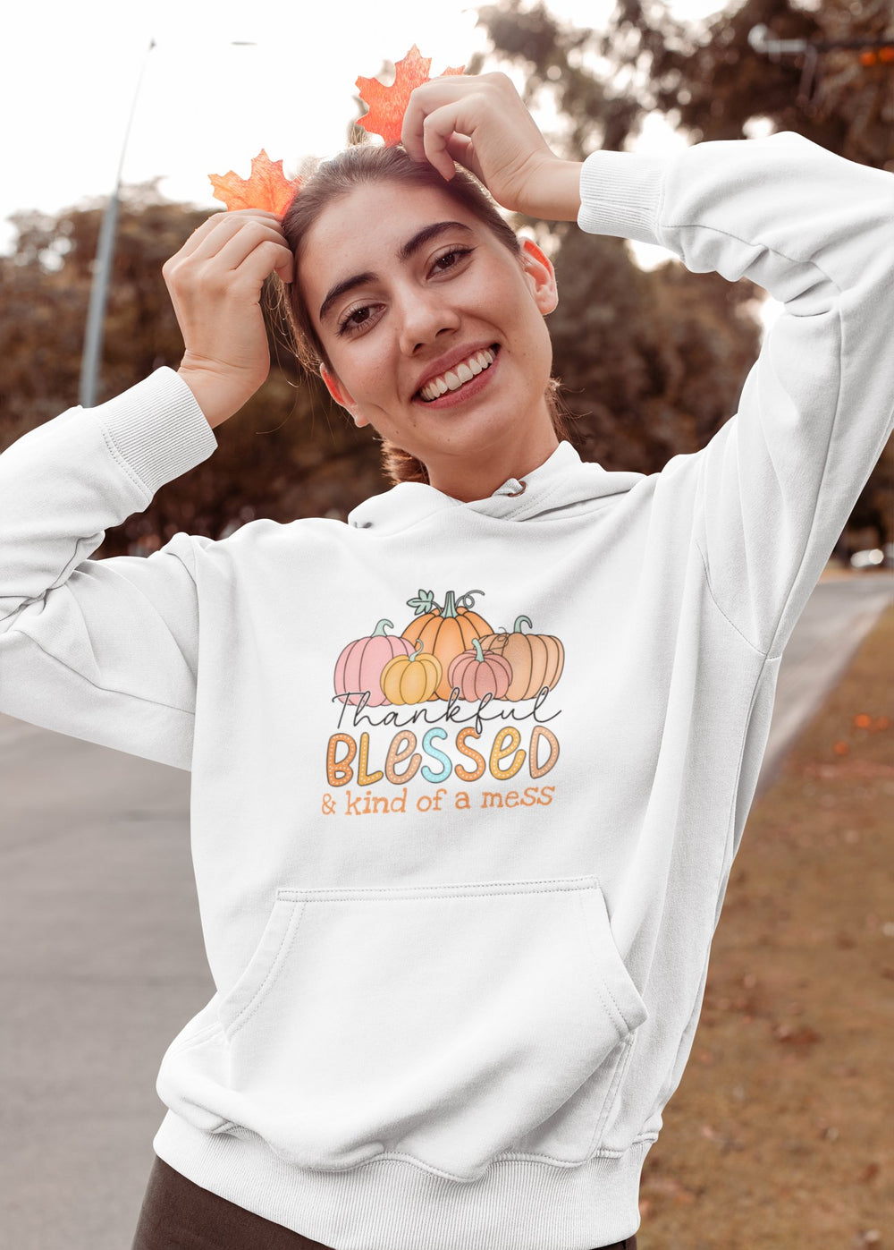 young woman holding leaves on her head like antlers wearing a hoodie